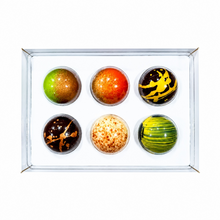 Load image into Gallery viewer, A boxed set of six decorative spherical chocolates arranged in a clear plastic tray on a white background. The spheres have varied patterns and colors, including green and gold, orange and red, black and yellow, dark brown and gold, cream and orange speckles, and green and black stripes.