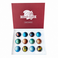 Load image into Gallery viewer, An open white gift box with a burgundy lid printed with the brand name 'CHOCOLATE ESCAPADE' and the words 'Artisan Confections'. Inside, twelve decorative round chocolates are arranged in a grid.