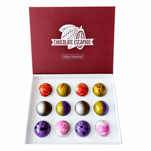Load image into Gallery viewer, An open white box of Chocolate Escapade artisan confections, showing twelve glossy, marbled chocolate truffles in red, green, purple, pink, and silver colors. The dark red lid features the white 'Chocolate Escapade' brand logo.