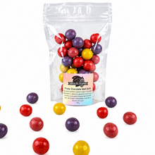 Load image into Gallery viewer, A clear stand-up pouch of fruity chocolate malt balls with a colorful label, shown on a white background with several loose red, purple, yellow, and orange chocolate malt balls around it.