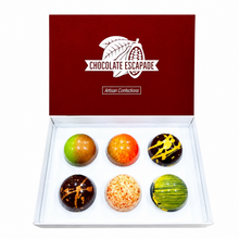 Load image into Gallery viewer, An open white gift box with a dark red lid printed with the brand name 'CHOCOLATE ESCAPADE' and the words 'Artisan Confections'. Inside, six glossy chocolate spheres in assorted colors and patterns are arranged in two rows of three on a white insert.
