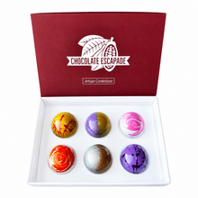 Load image into Gallery viewer, An open white gift box with a dark red lid printed with the brand name 'CHOCOLATE ESCAPEDE' and 'Artisan Confections'. Inside are six glossy, round decorated chocolates arranged in two rows of three on a white tray.
